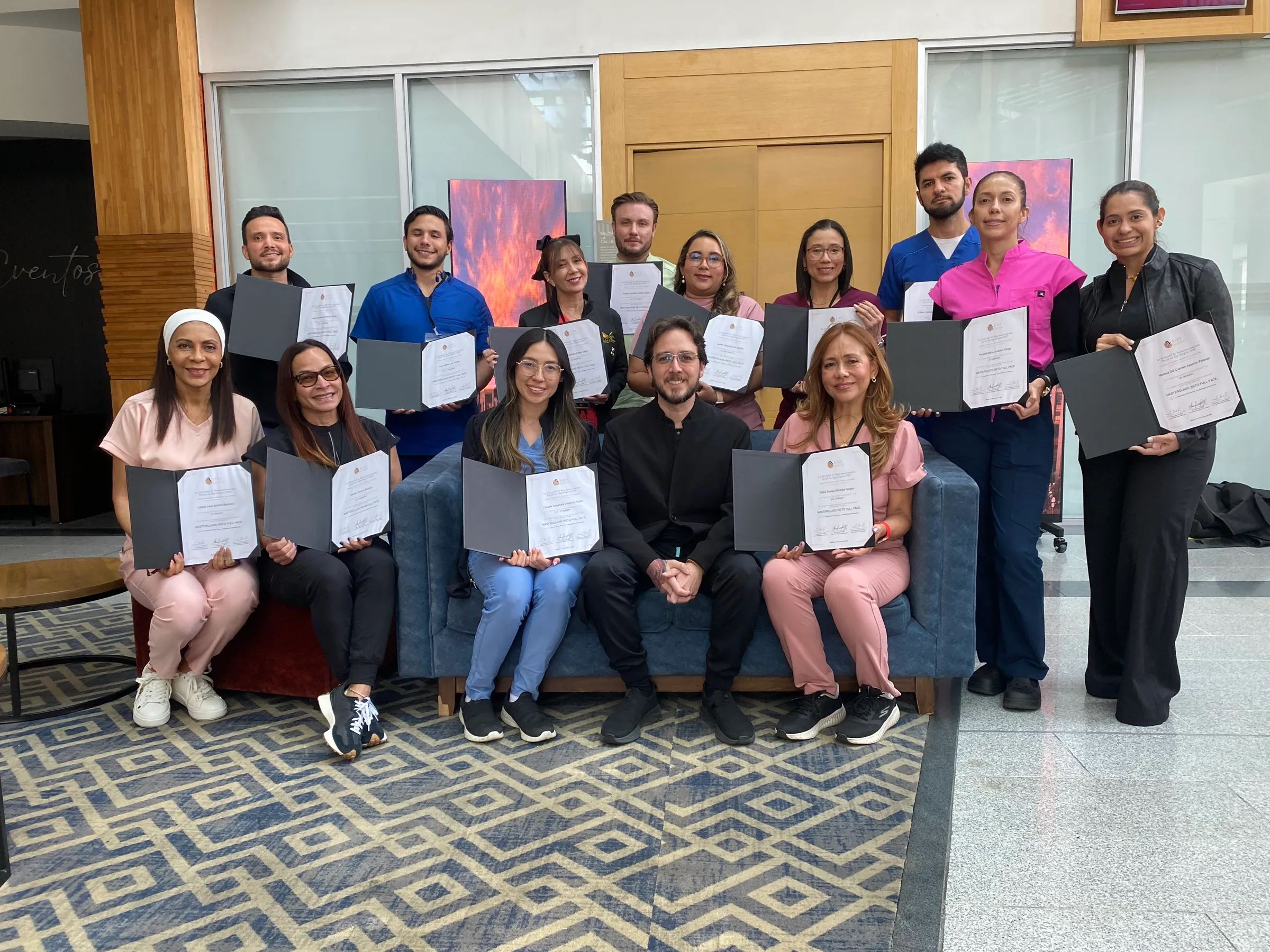 Grupo de médicos con sus diplomas al cierre de una master class, sentados y de pie alrededor del Dr. Luis Alberto Parra